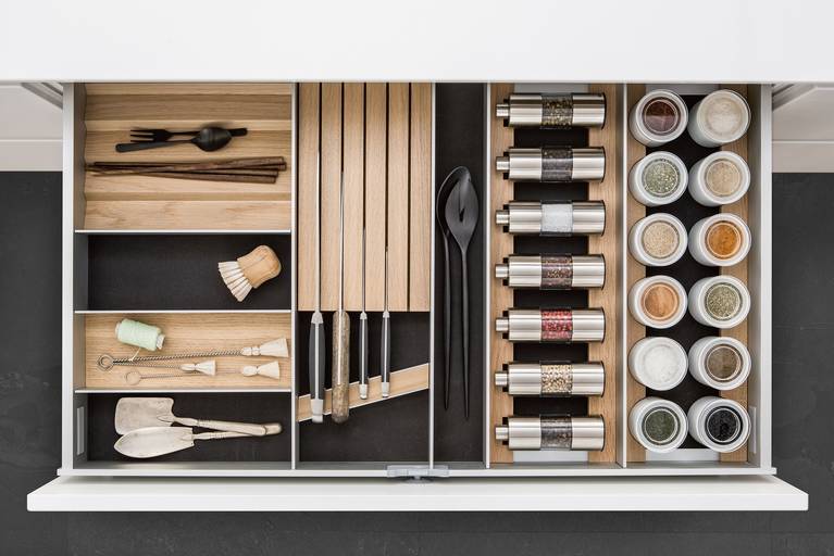 SieMatic aluminum kitchen interior accessories in light oak offer space for spice mills, porcelain jars and knives.
