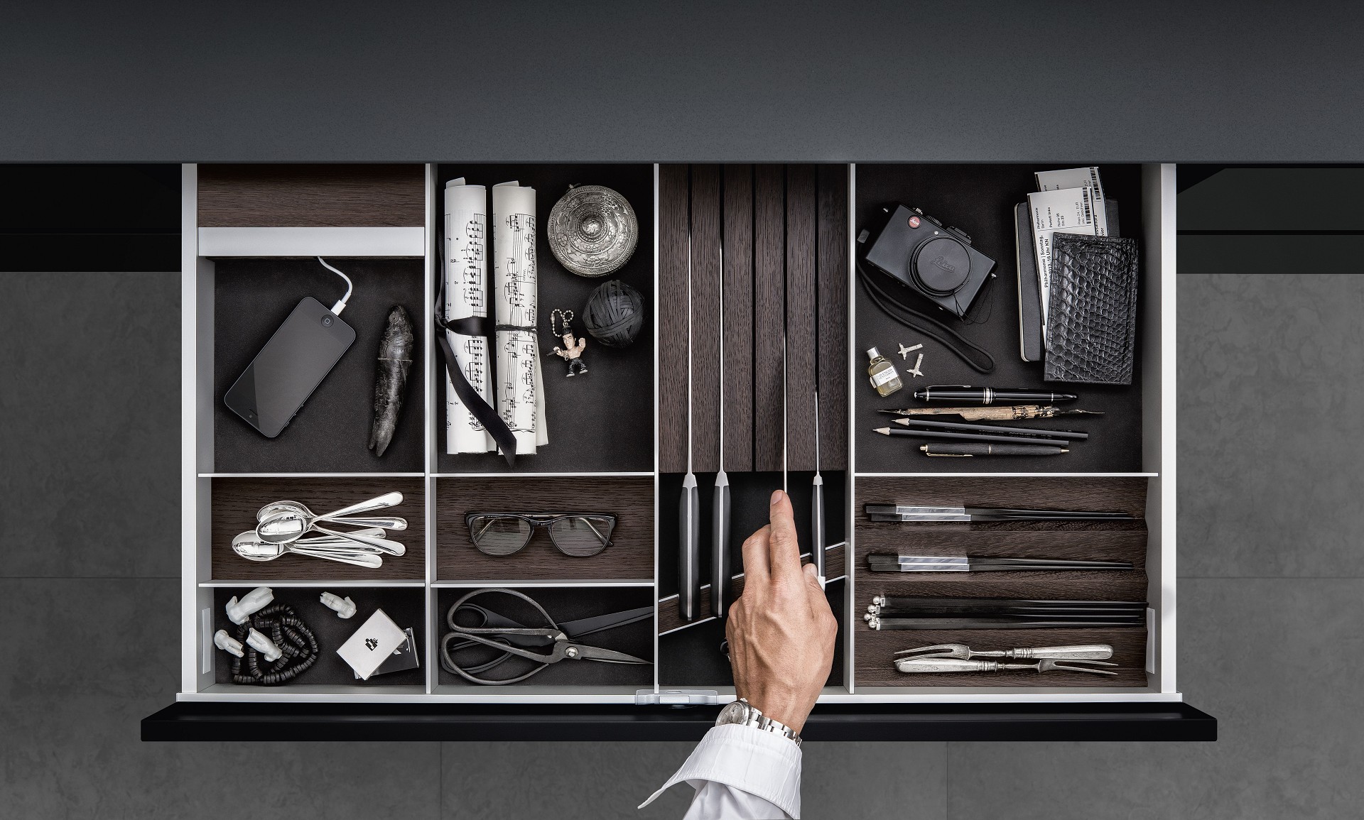 SieMatic aluminum kitchen interior accessories in dark smoked chestnut provide a place for iPhone, cutlery and knives.
